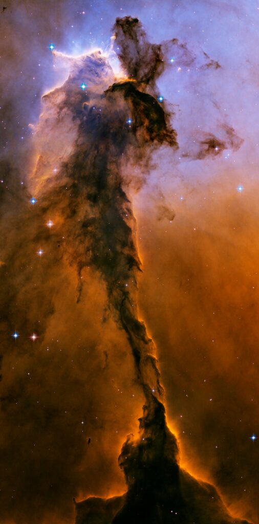 Appearing like a winged fairy-tale creature poised on a pedestal, this object is actually a billowing tower of cold gas and dust rising from a stellar nursery called the Eagle Nebula. The soaring tower is 9.5 light-years or about 90 trillion kilometres high, about twice the distance from our Sun to the next nearest star. Stars in the Eagle Nebula are born in clouds of cold hydrogen gas that reside in chaotic neighbourhoods, where energy from young stars sculpts fantasy-like landscapes in the gas. The tower may be a giant incubator for those newborn stars. A torrent of ultraviolet light from a band of massive, hot, young stars [off the top of the image] is eroding the pillar. The starlight also is responsible for illuminating the tower's rough surface. Ghostly streamers of gas can be seen boiling off this surface, creating the haze around the structure and highlighting its three-dimensional shape. The column is silhouetted against the background glow of more distant gas. The edge of the dark hydrogen cloud at the top of the tower is resisting erosion, in a manner similar to that of brush among a field of prairie grass that is being swept up by fire. The fire quickly burns the grass but slows down when it encounters the dense brush. In this celestial case, thick clouds of hydrogen gas and dust have survived longer than their surroundings in the face of a blast of ultraviolet light from the hot, young stars. Inside the gaseous tower, stars may be forming. Some of those stars may have been created by dense gas collapsing under gravity. Other stars may be forming due to pressure from gas that has been heated by the neighbouring hot stars. The first wave of stars may have started forming before the massive star cluster began venting its scorching light. The star birth may have begun when denser regions of cold gas within the tower started collapsing under their own weight to make stars. The bumps and fingers of material in the centre of the tower are examples of these ste