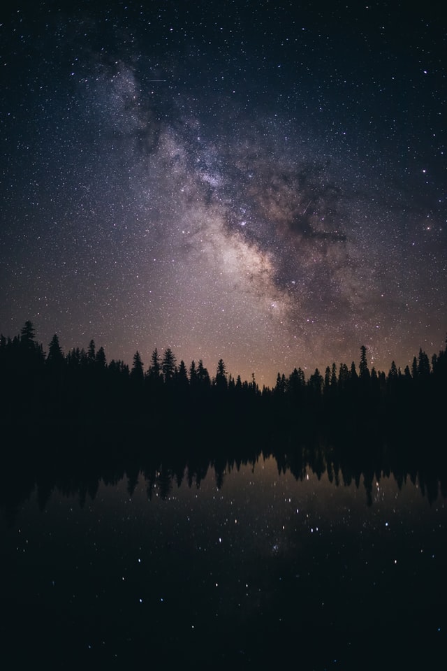 Milky Way over forest and lake